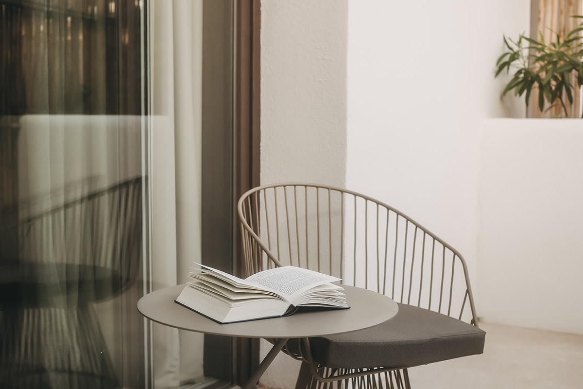 Acogedor balcón en la habitación Pino del Barefoot Hotel Mallorca con asientos, mesa y libro abierto.