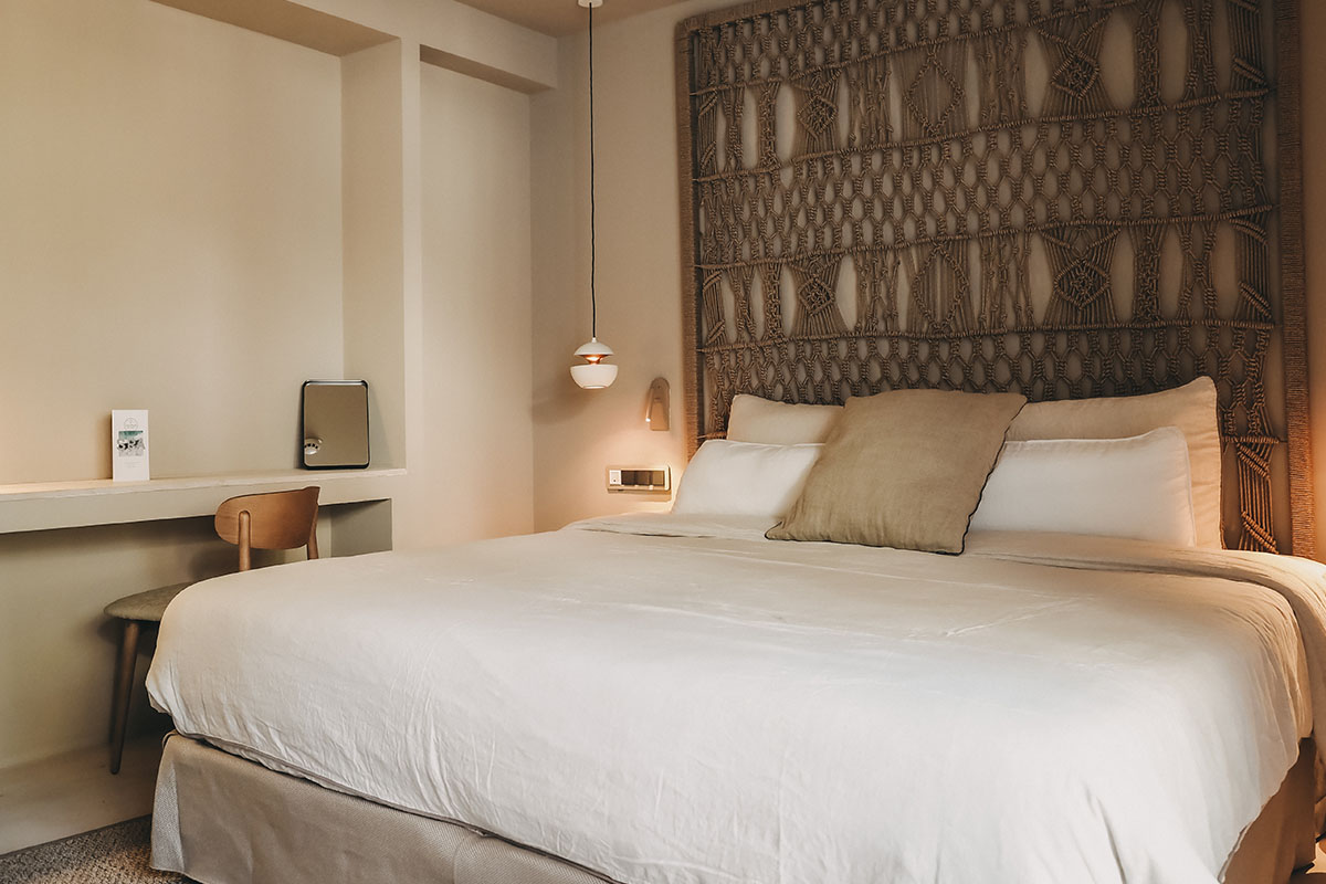 Acogedora cama en la habitación Pino del Barefoot Hotel Mallorca con cabecero y almohadas decorativos.