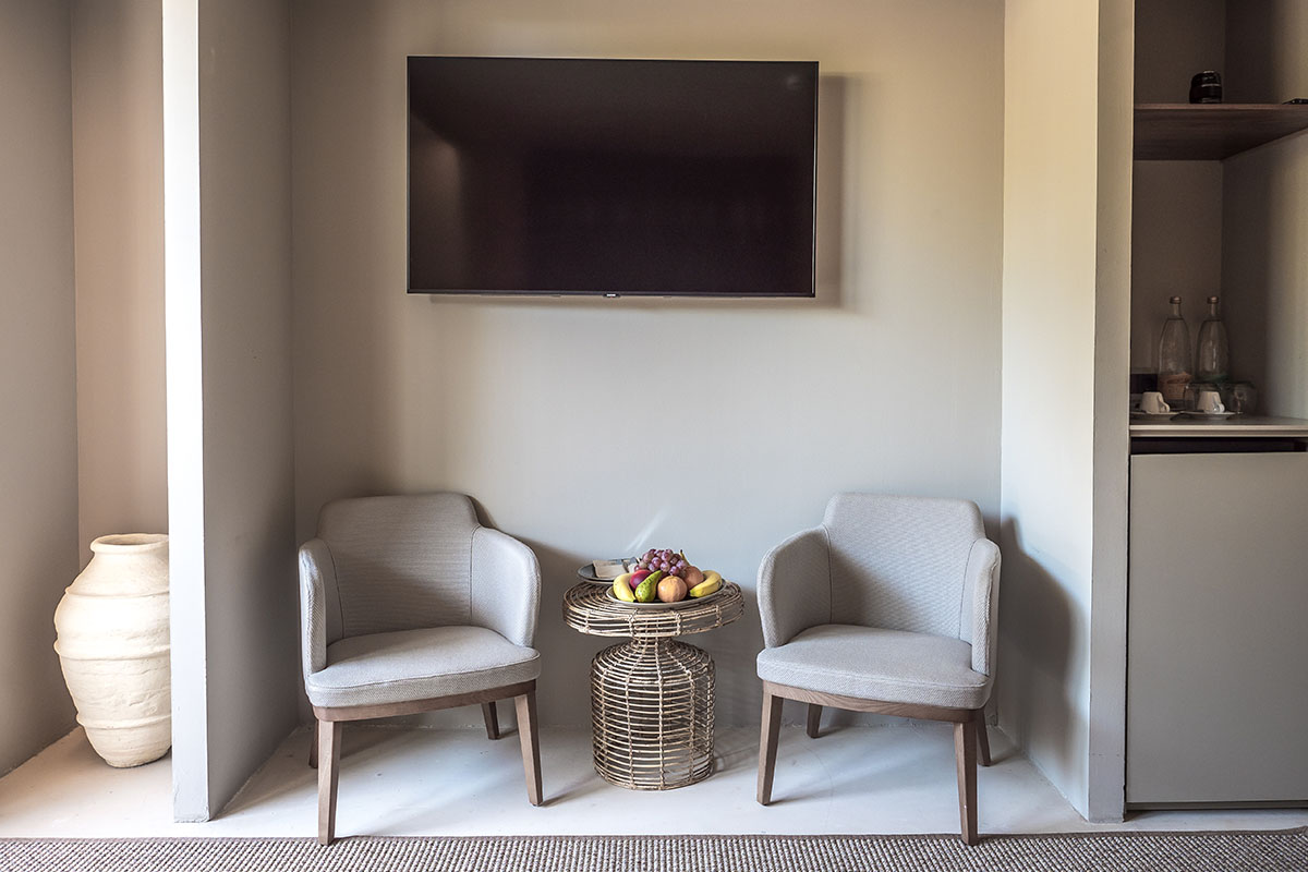 Acogedora zona de estar en la habitación Pino del Barefoot Hotel Mallorca con dos sillones, mesa de ratán y frutero.