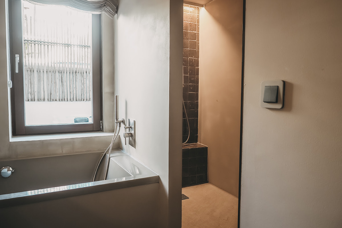 Luminoso cuarto de baño con bañera y ducha a ras de suelo en la habitación Pueblo del Barefoot Hotel Mallorca para relajantes momentos de bienestar.