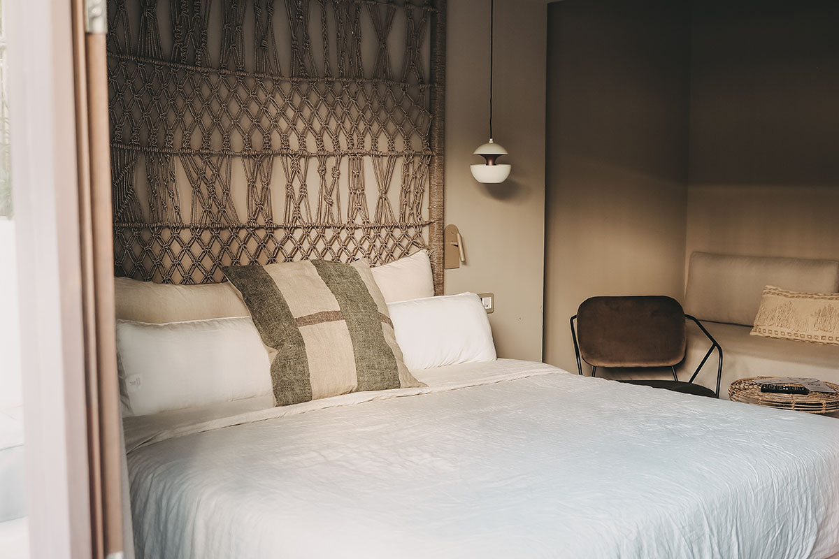 Acogedora zona de dormitorio en la habitación Pueblo del Hotel Barefoot Mallorca con cabecero y almohadas decorativas.