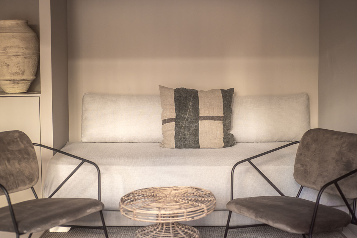 Acogedora zona de estar en la habitación Pueblo del Barefoot Hotel Mallorca con sofá y modernos sillones.