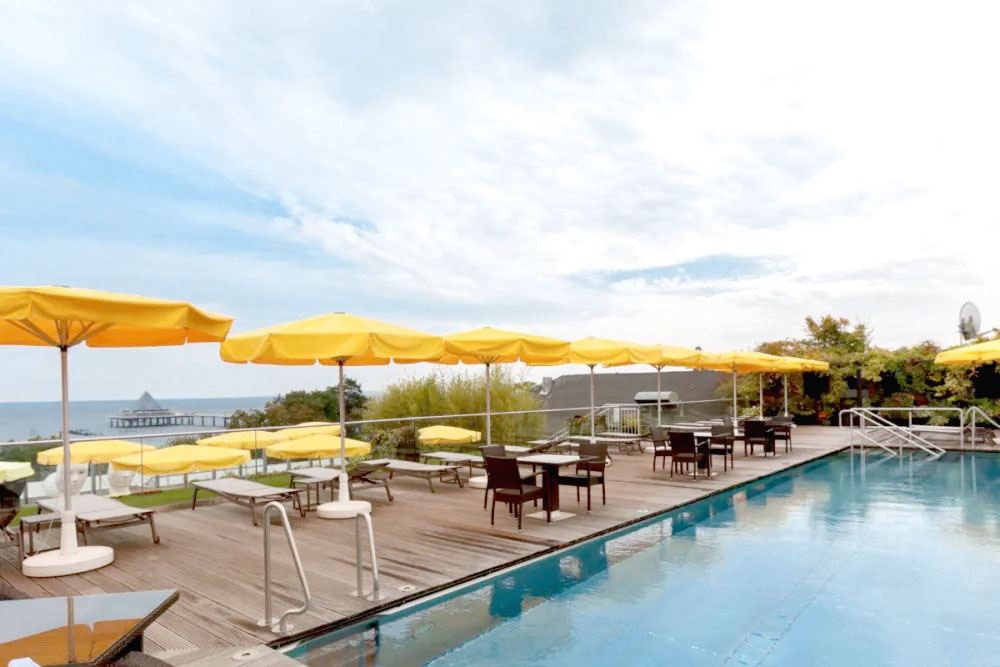 Pool terrace with parasols and a view of the Heringsdorf pier for the perfect summer vacation at the Hotel Kaiserhof.
