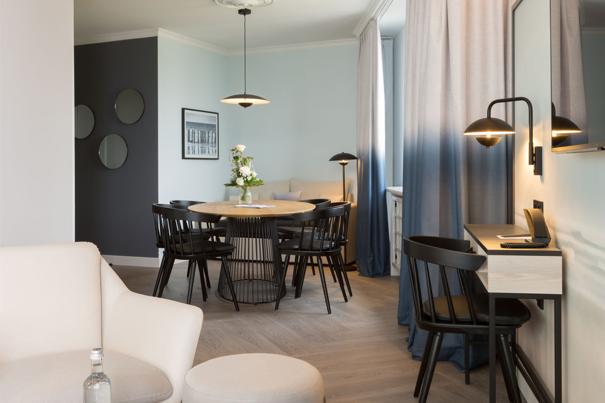 Living area of the Kaisersuite with dining table, chairs, desk and modern design, ideal for work and relaxation at the Hotel Kaiserhof.