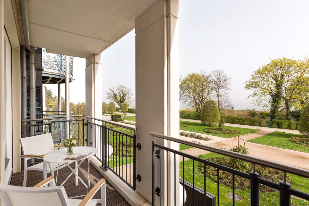 Balcony of a themed suite in the Hotel Kaiserhof Heringsdorf on Usedom with table, chairs and view of the garden.