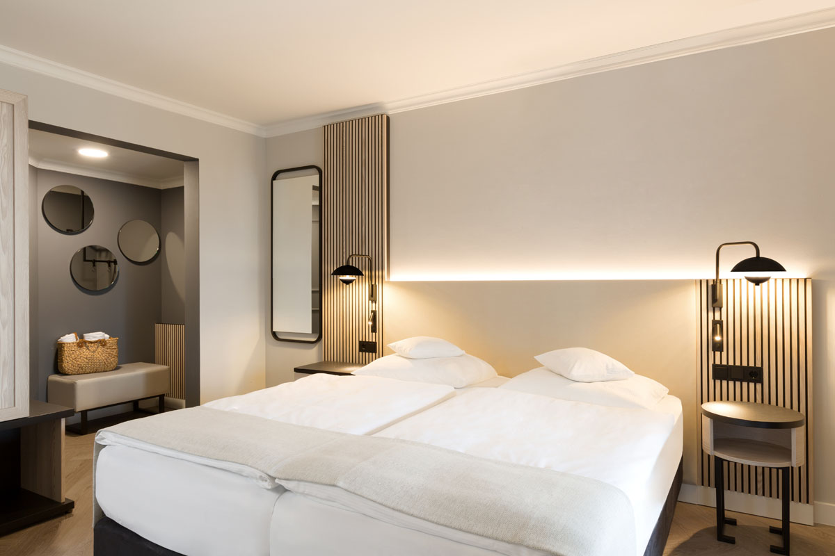 Modern double bed in the themed suite of the Hotel Kaiserhof Heringsdorf with elegant lighting and minimalist design.