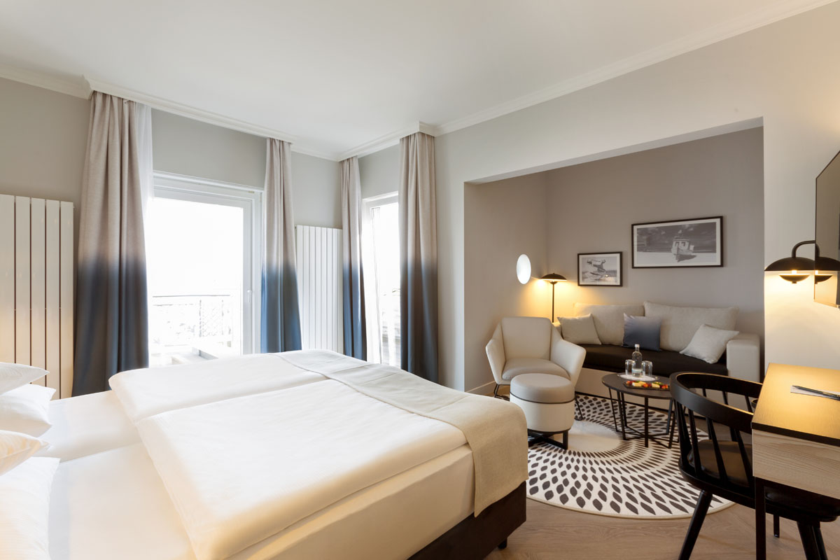 View of a themed suite with sleeping area, sofa, armchair and dining table at the Hotel Kaiserhof Heringsdorf on Usedom.