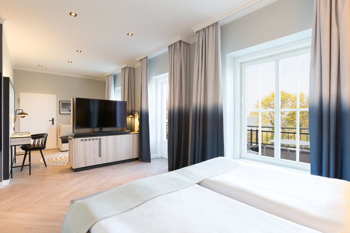 View into the sleeping area of a themed suite with double bed and balcony at the Hotel Kaiserhof Heringsdorf on Usedom.