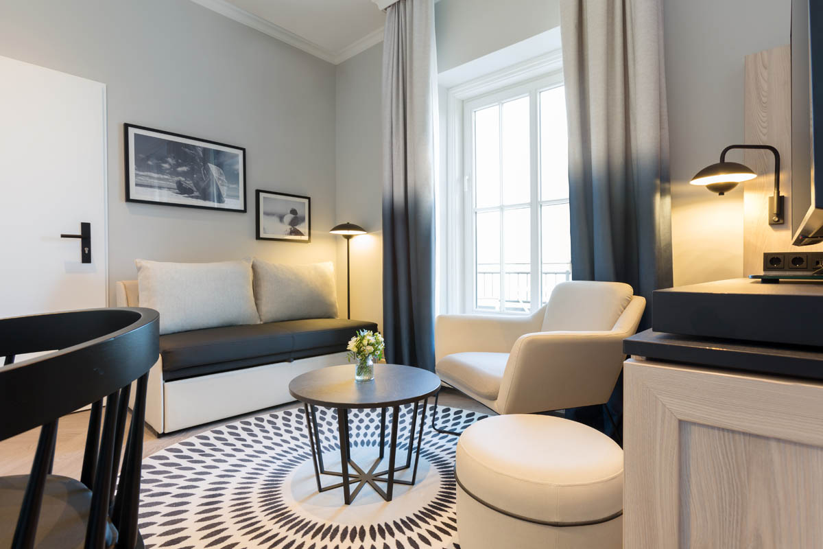 Modern seating area with sofa, armchair and round table in a themed suite at the Hotel Kaiserhof Heringsdorf on Usedom.