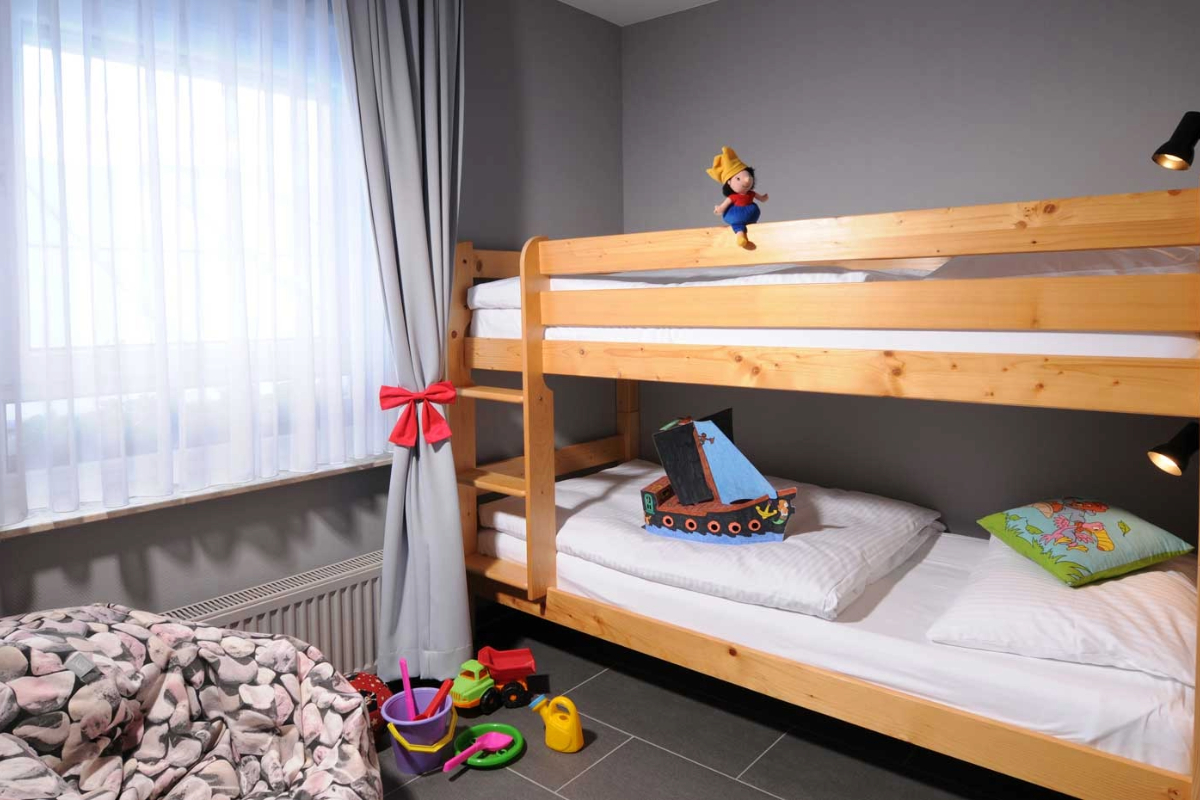 Child-friendly bunk bed with toys and colorful pillows in the family room at the Hotel Kaiserhof Heringsdorf.