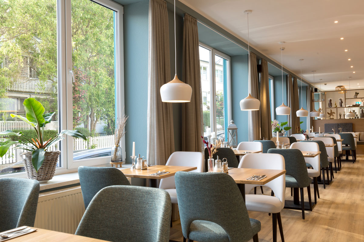 Frühstücksbereich des Koopmanns Hotel &amp; Lädchen, ausgestattet mit eleganten Tischen, Stühlen und Dekorationen.