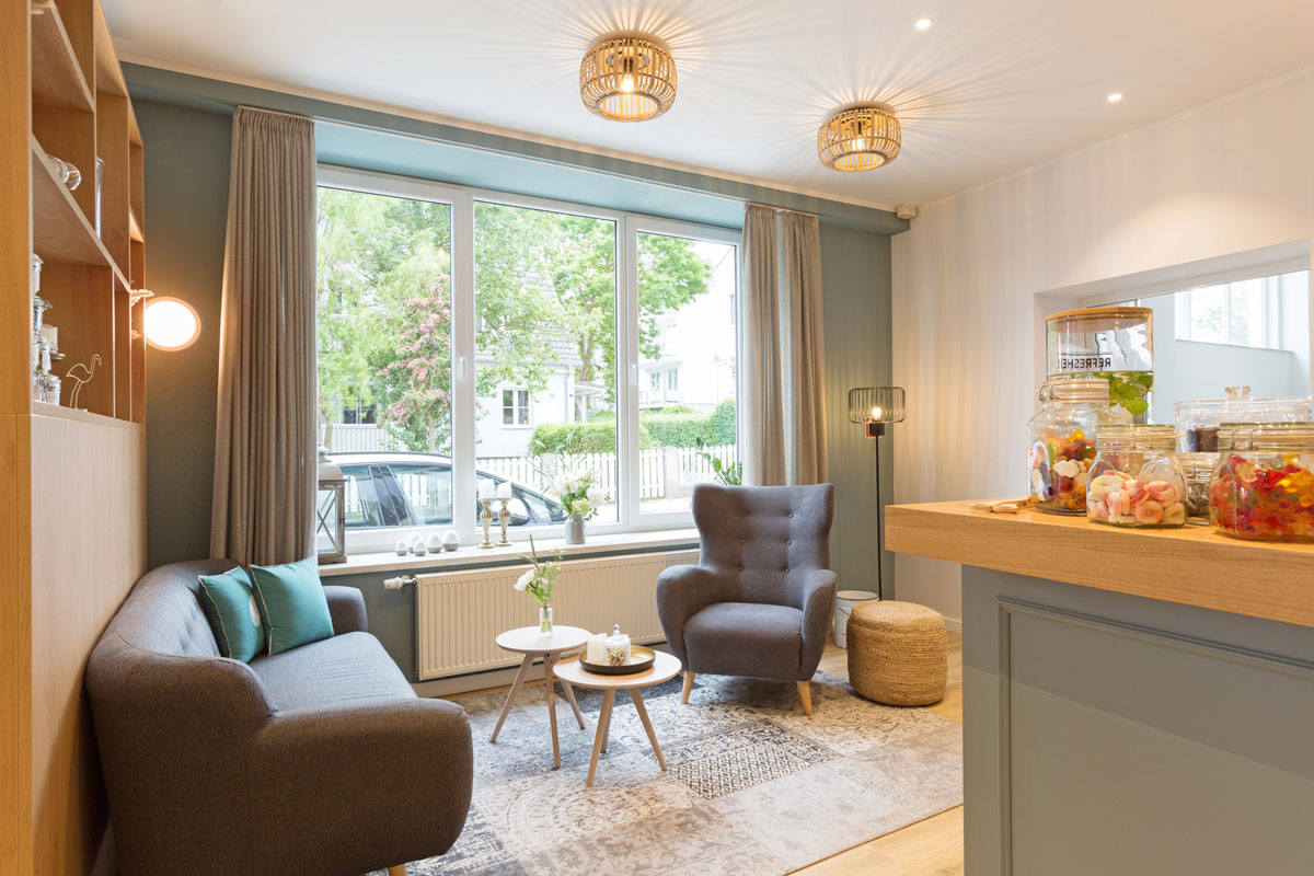 Gemütliche Lounge im Koopmanns Hotel mit Sesseln, Sofas und kleinen Tischen, ideal für Entspannung oder Snacks.