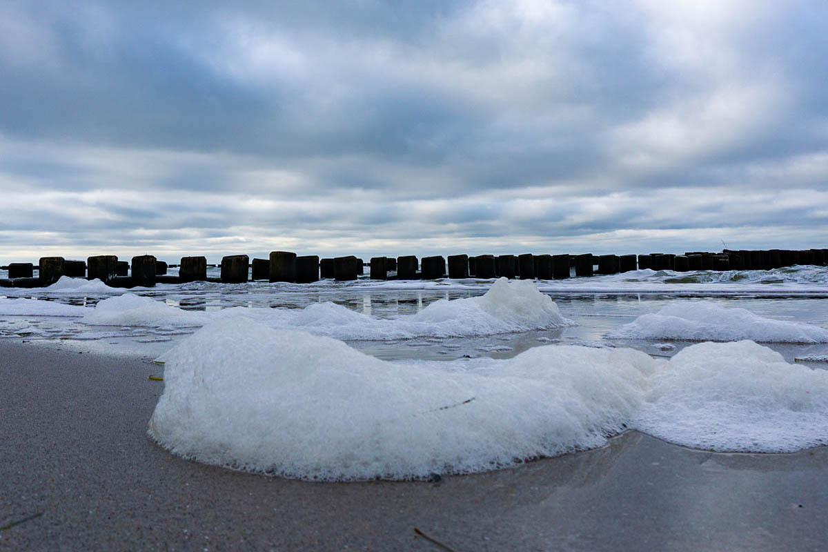 Schaumkronen der Ostsee rollen an den Strand mit dramatischer Himmel über dem Meer in ihrem Urlaub im Hotel Seezeichen.