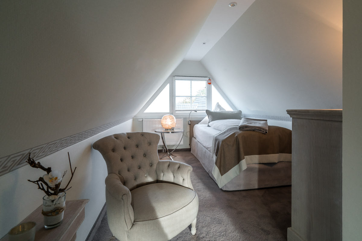 Helles Dachzimmer mit gemütlichem Einzelbett im Ferienhaus Ostseeperle vom Hotel Künstlerquartier Seezeichen.