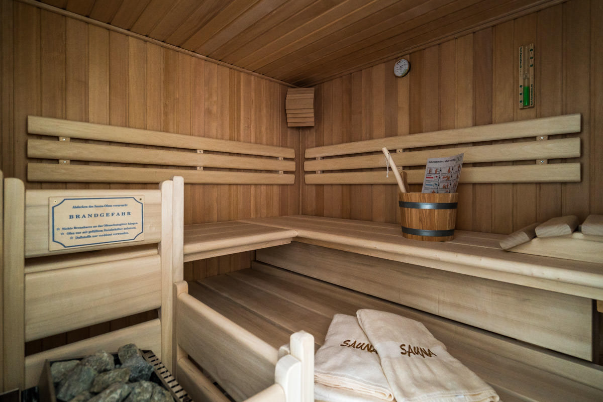 Private Sauna aus hellem Holz im Ferienhaus Sonneninsel mit Handtüchern, Teil des Hotel Künstlerquartier Seezeichen.