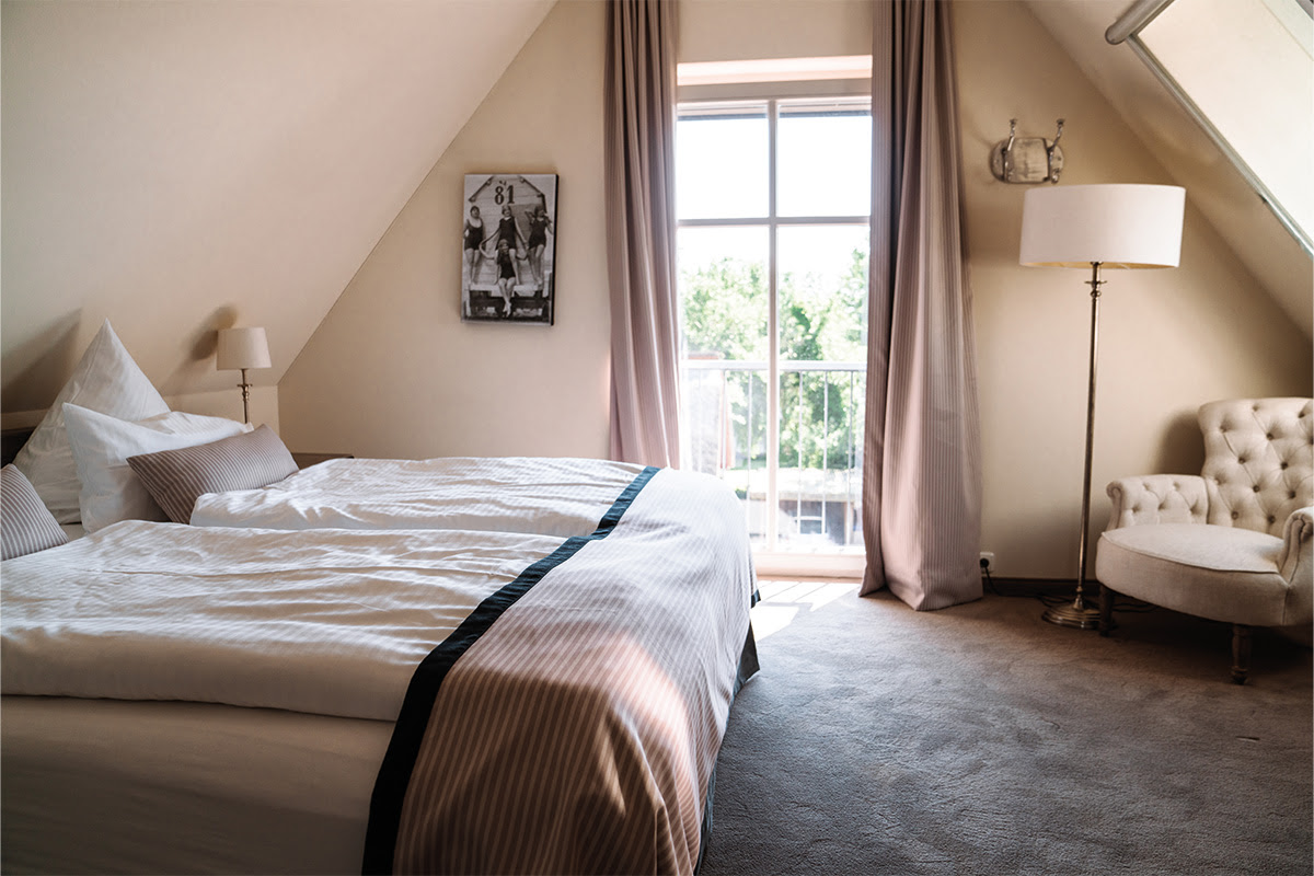 Gemütliches Schlafzimmer in der Ferienwohnung Dünenpark mit großem Bett und Meerblick, Teil des Hotel Künstlerquartier Seezeichen.