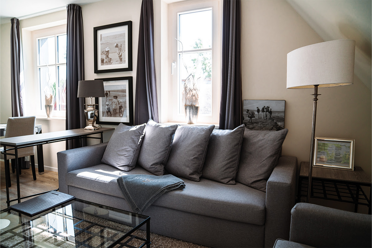 Heller, moderner Wohnbereich der Ferienwohnung Dünenpark vom Hotel Künstlerquartier Seezeichen mit gemütlichem Sofa.