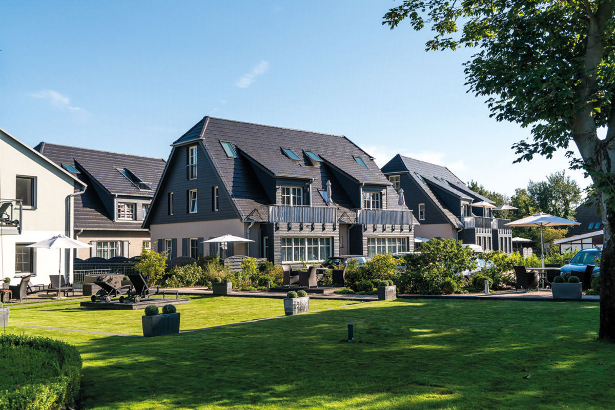 Sonnige Außenansicht der Ferienwohnung Dünenpark des Hotels Künstlerquartier Seeziechen mit großer Grünfläche.