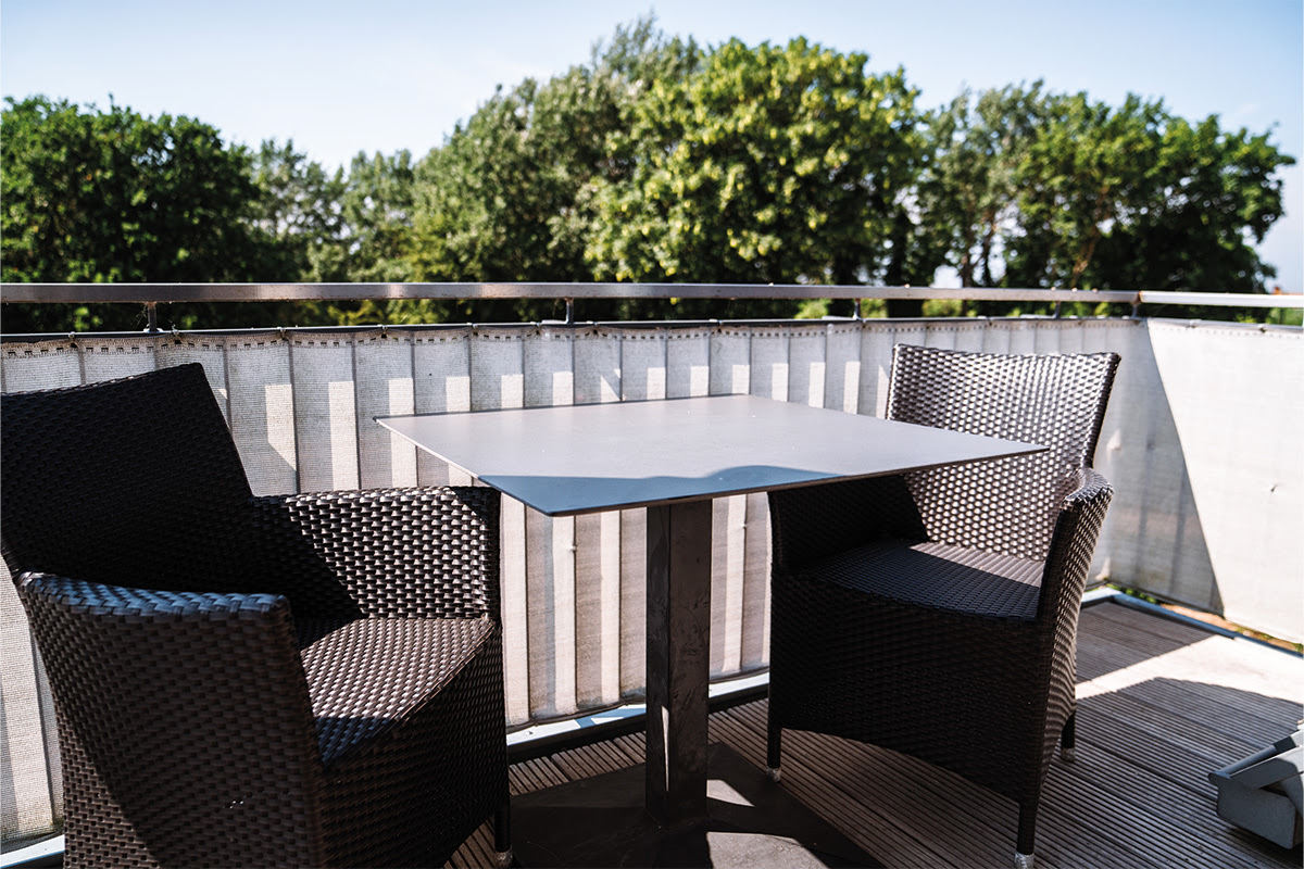 Sonniger Balkon der Ferienwohnung Dünenpark im Hotel Künstlerquartier Seezeichen mit bequemen Sitzgelegenheiten und Seeblick.