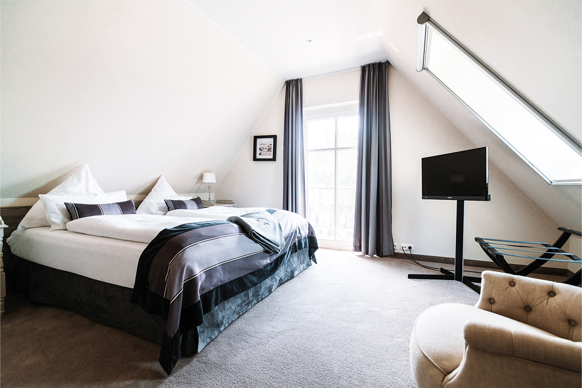 Gemütliches Schlafzimmer der Ferienwohnung Seeigel des Hotels Künstlerquartier Seezeichen mit großem Bett und TV.