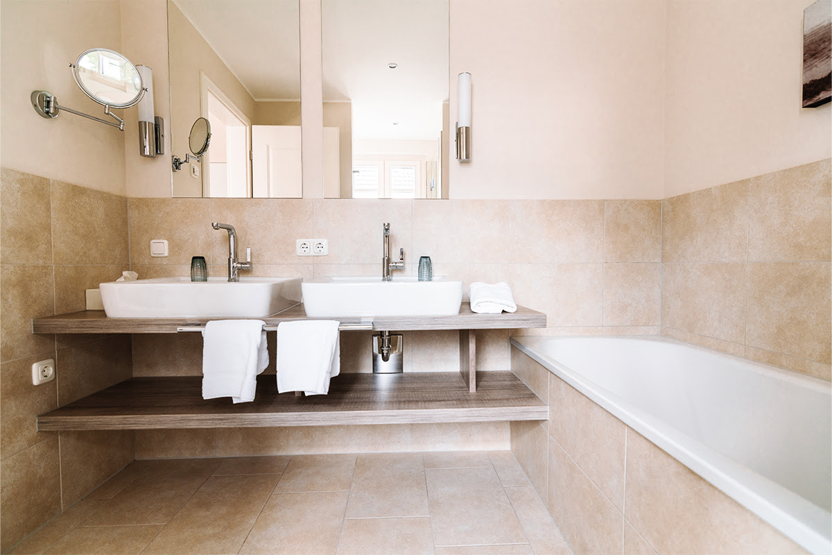 Modernes Badezimmer in der Ferienwohnung Seepferd mit zwei Waschbecken und Badewanne im Hotel Künstlerquartier Seezeichen.