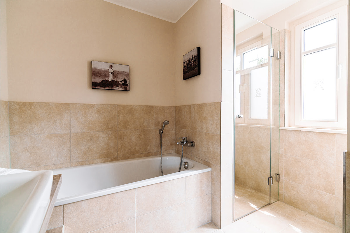 Geräumiges Badezimmer der Ferienwohnung Seeipferd im Hotel Künstlerquartier Seezeichen mit Badewanne und Glasdusche.