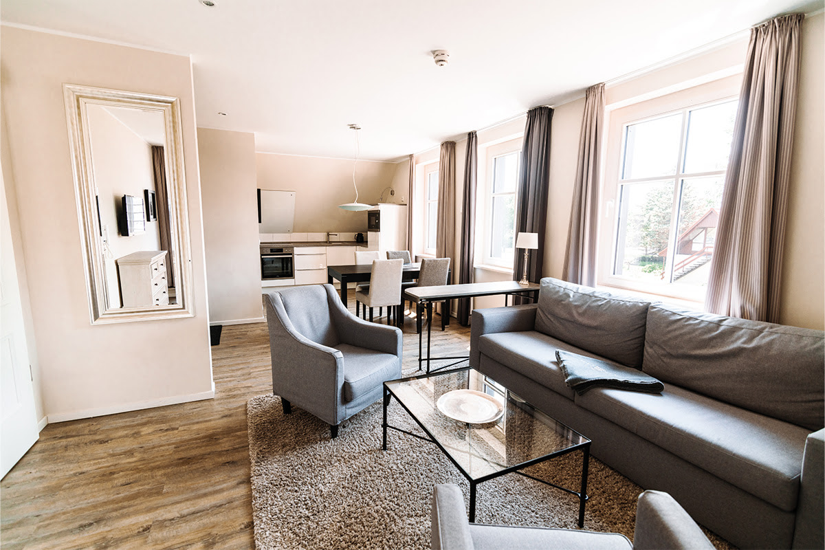 Geräumiger Wohnbereich mit Esstisch und Lounge-Möbeln in der Ferienwohnung Seepferd im Dünenpark an der Ostsee.