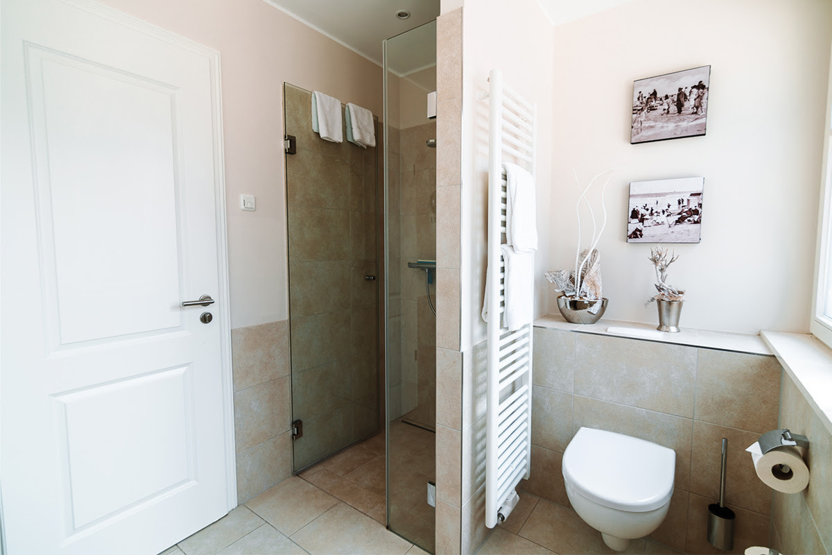 Helles Badezimmer mit stilvollem Interieur und Glasdusche in der Ferienwohnung Stranddistel im Hotel Künstlerquartier Seezeichen.