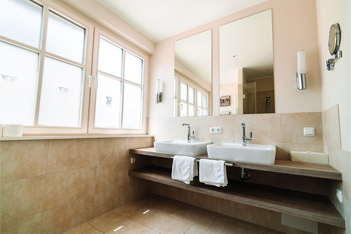 Doppelwaschbecken im Badezimmer der Ferienwohnung Stranddistil mit Spiegel und Handtüchern im Dünenpark Ahrenshoop.