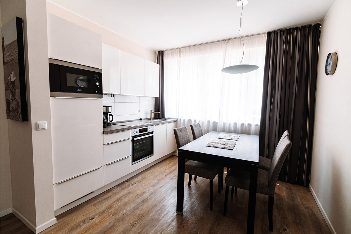 Offene Küche mit Esstisch in der Ferienwohnung Stranddistel im Dünenpark in Ahrenshoop mit hochwertigen Geräten.