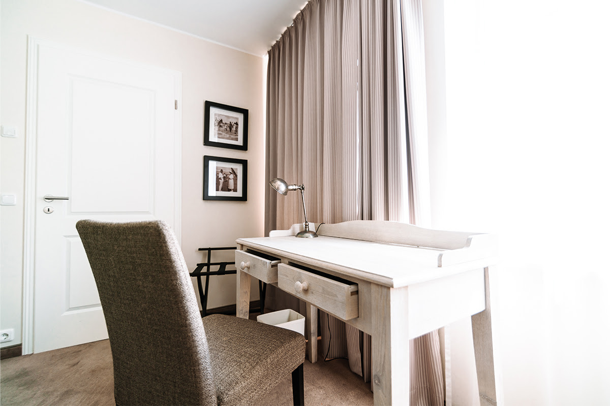 Stilvoller Schreibtisch mit bequemer Stuhl im hellen Raum der Ferienwohnung Stranddistel im Hotel Künstlerquartier Seezeichen.