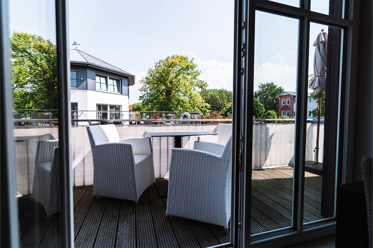 Moderner Balkon mit Sitzgelegenheiten und Ausblick ins Grüne in der Ferienwohnung Strandduene im Dünenpark Ahrenshoop.