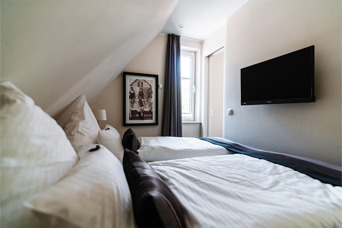 Gemütliches Schlafzimmer mit Tageslicht und großem Bett in der Ferienwohnung Strandnixe im Hotel Künstlerquartier Seezeichen.