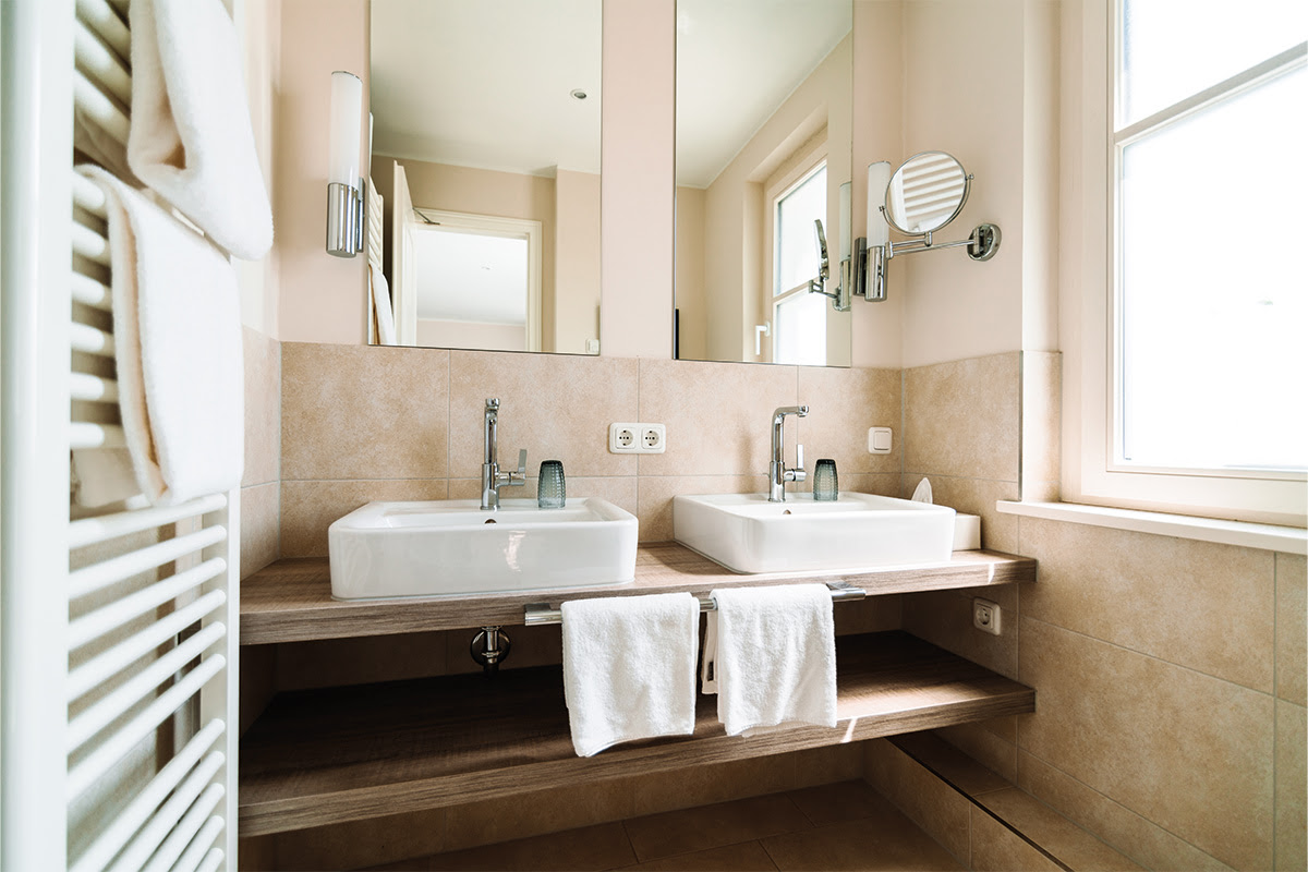 Badezimmer mit Doppelwaschbecken und Handtüchern in der Ferienwohnung Strandperle des Hotel Künstlerquartier Seezeichen.