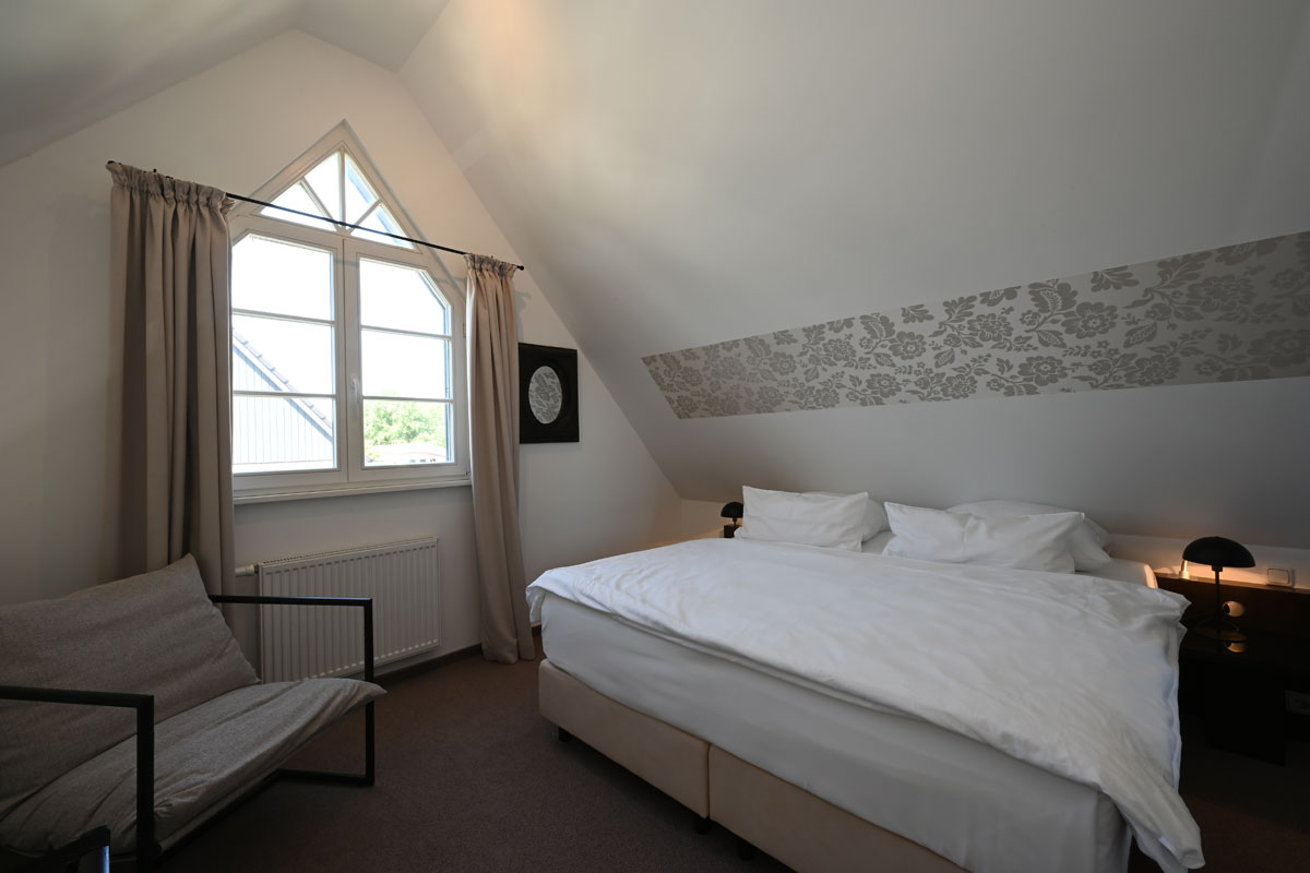 Gemütliches Schlafzimmern mit einladendem Bett in der Ferienwohnung Seestern im Hotel Künstlerquartier Seezeichen.