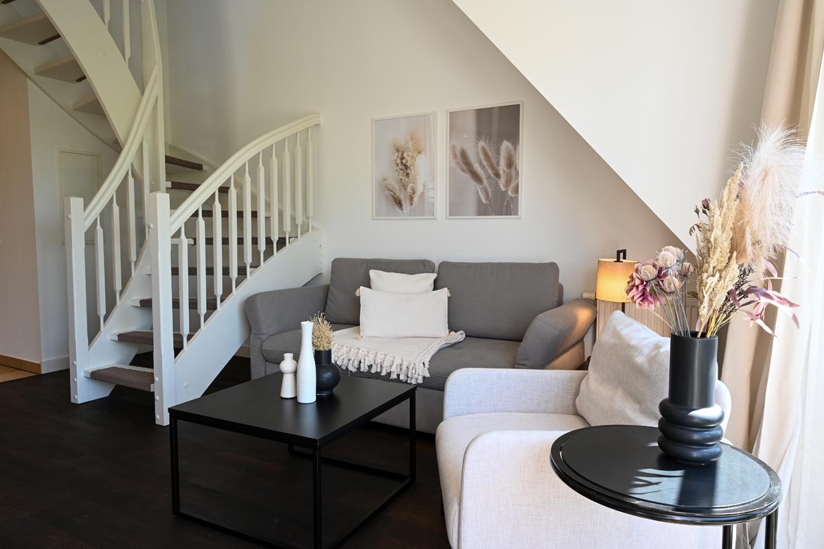 Geschmackvoll eingerichtetes Wohnzimmer der Ferienwohnung Seestern im Hotel Künstlerquartier Seezeichen neben deiner Treppe.