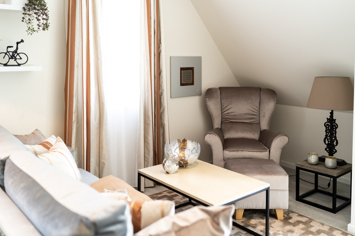 Gemütlicher Wohnbereich mit hellen Polstermöbeln der Ferienwohnung Strandjuwel im Hotel Künstlerquartier Seezeichen.