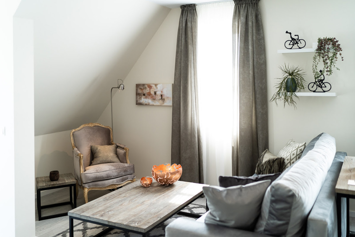 Wohnbereich mit Sofa, Sessel und Couchtisch unter einer Dachschräge der Ferienwohnung Strandoase in der Strandvilla Ahrenshoop.