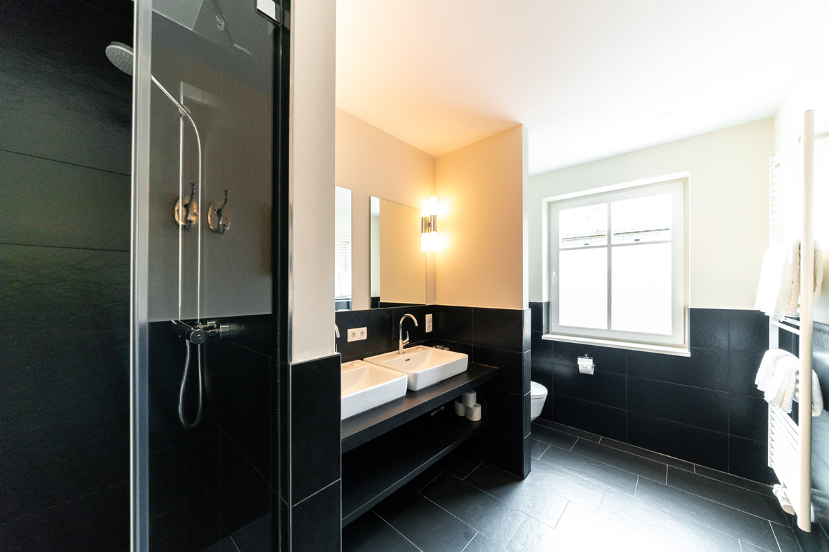 Geräumiges Badezimmer mit Regendusche, Doppelwaschbecken und Tageslicht der Ferienwohnung Strandtraum in Ahrenshoop.