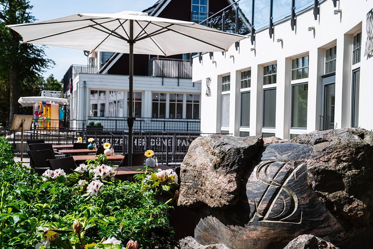 Terrace of the Hotel Künstlerquartier Seezeichen with parasol and flowers during a stay in the Seezeichen room.