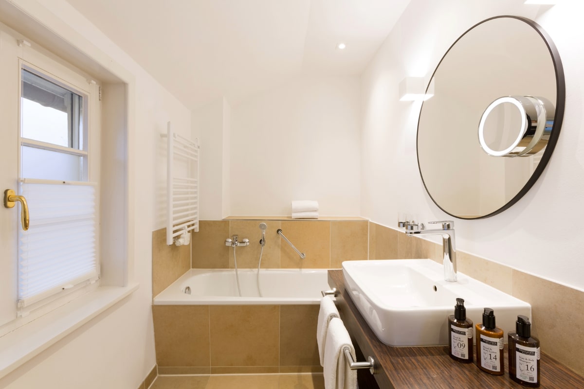 Bright, modern bathroom in the Elisabeth Gallery Suite in the Hotel Künstlerquartier Seezeichen with natural light and beauty products.