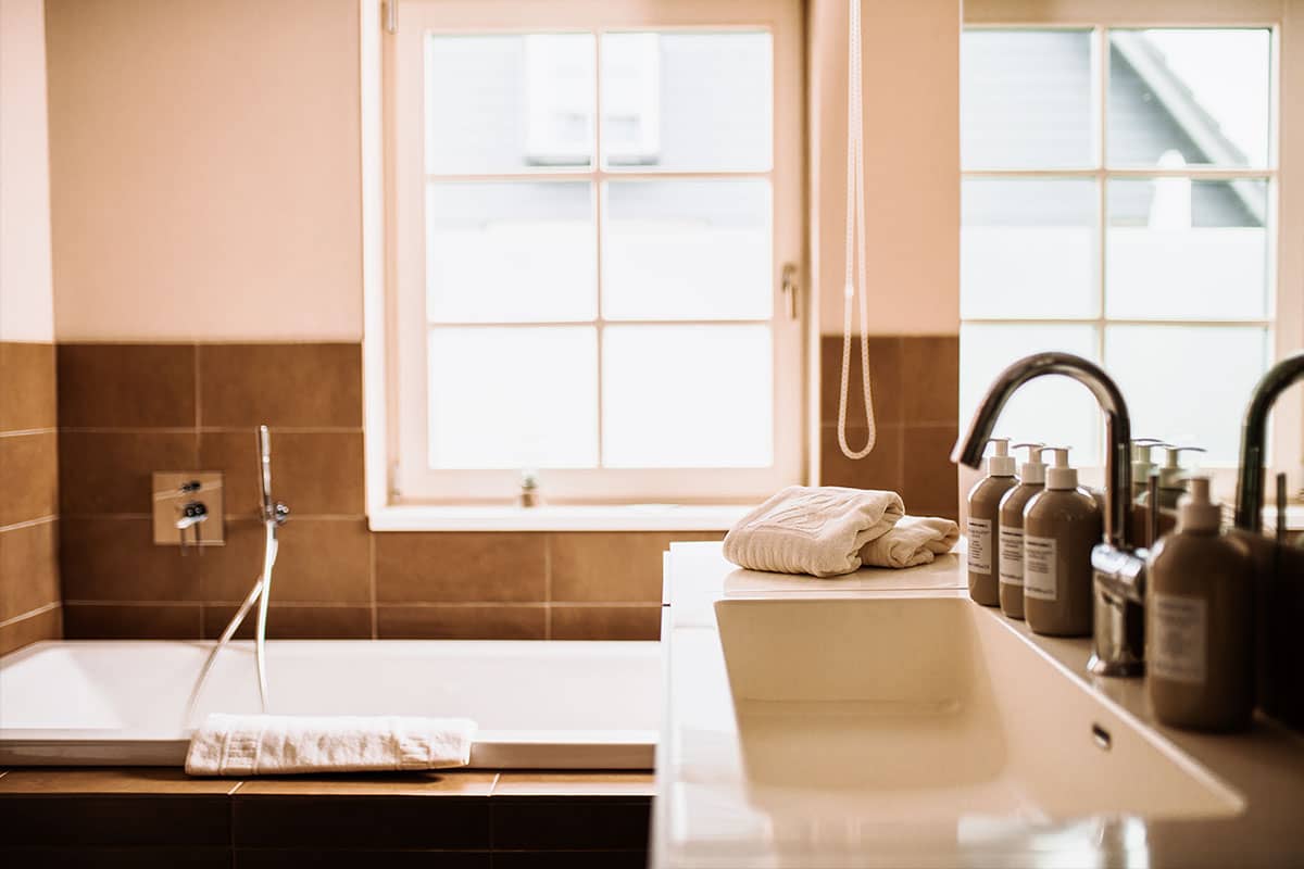 Stylish bathroom with bathtub, washbasin and cosmetics in the Junior Suite of the Hotel Künstlerquartier Seezeichen.
