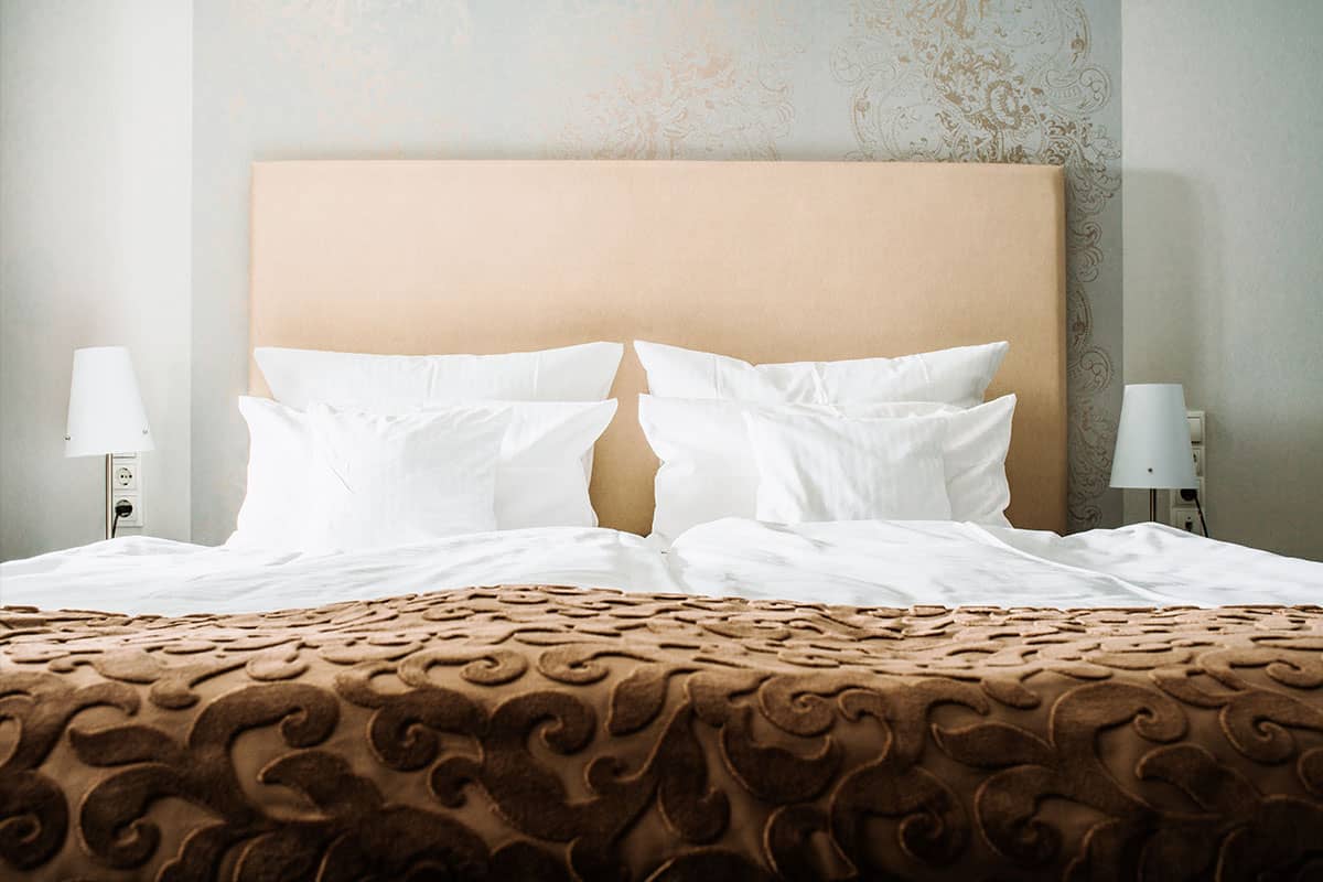 King-size bed with soft pillows and an elegant brown comforter in the Junior Suite at Hotel Künstlerquartier Seezeichen.