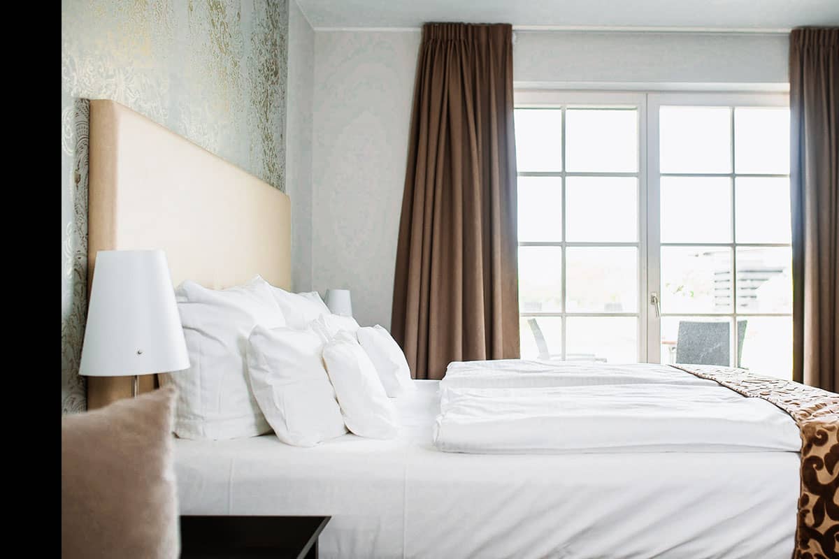 Large bed with soft pillows in the bedroom of the Junior Suite at Hotel Künstlerquartier Seezeichen.