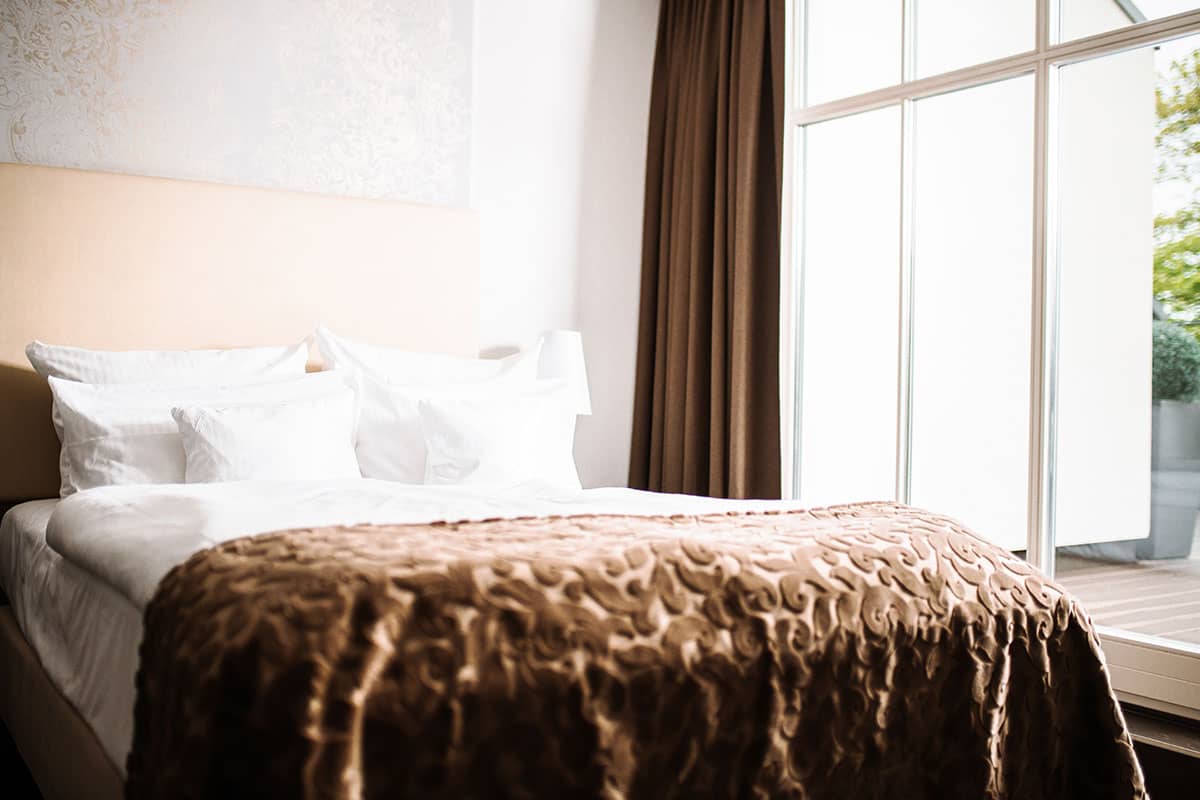 A spacious double bed with elegant bed linen in the Comfort double room at the Hotel Künstlerquartier Seezeichen.