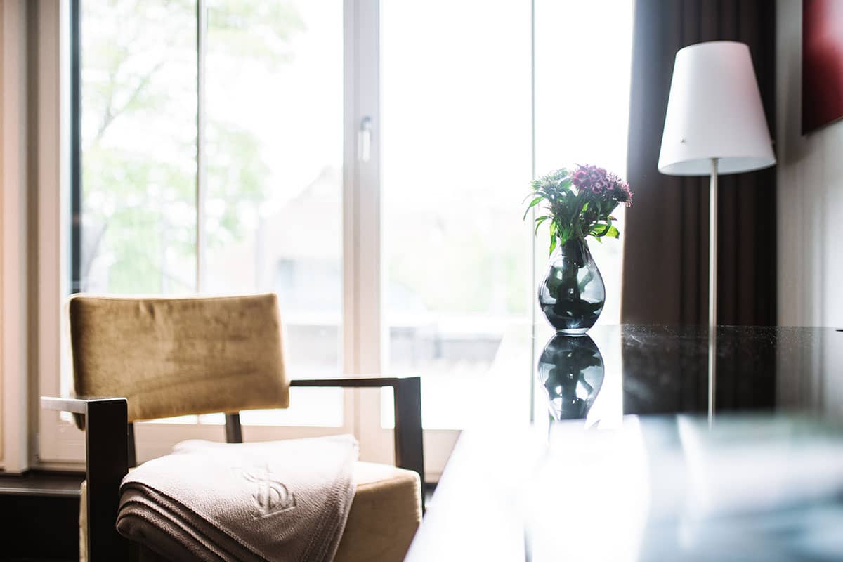 A cozy chair and flower arrangement in the Comfort double room of the Hotel Künstlerquartier Seezeichen.