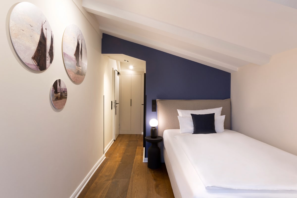 Cozy single room with sloping ceilings, maritime wall decoration and modern bed in the Elisabeth von Eicken Hotel.