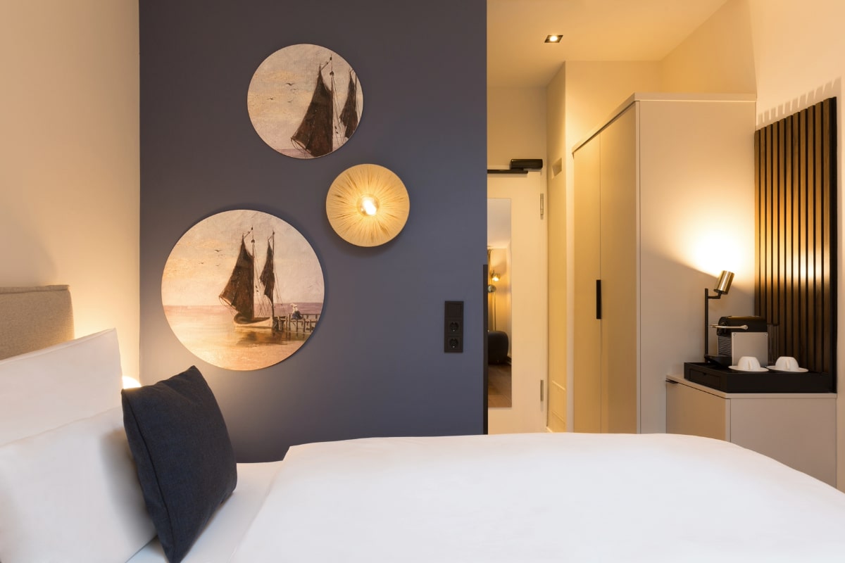 Single room with maritime wall decoration, stylish furnishings and comfortable bed at the Elisabeth von Eicken Hotel.