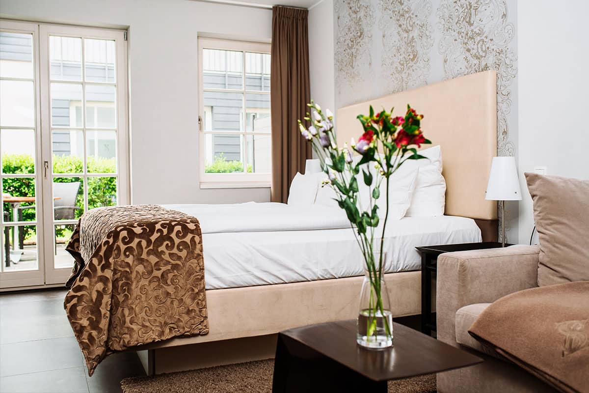 Comfortable double bed in the first-class double room in the Hotel Künstlerquartier Seezeichen with elegant furnishings and natural light.