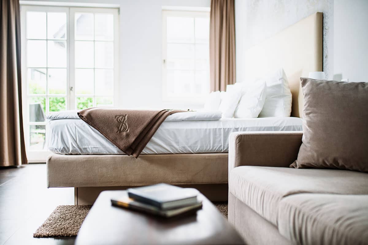 Sitting area with sofa and table next to a bed in the first-class double room of the Hotel Künstlerquartier Seezeichen.